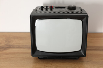Retro tv set on wooden shelf against white wall