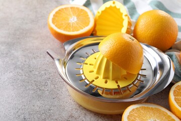 Juicer and oranges on grey table, closeup