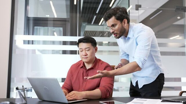 Angry boss quarreling with upset subordinate while sitting at laptop at workplace in business office. Furious employer arguing talking about problems. Dissatisfied manager unhappy with work results