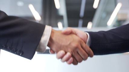 Close up of business handshake symbolizing teamwork and cooperation. Two male professionals shaking hands after sealing a deal in a modern office. Concept of partnership among colleagues. Mutual trust