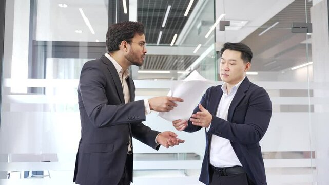 Two angry businessmen arguing intensely in modern office setting, showcasing conflict and emotion during heated business discussion or disagreement. Colleagues aggressive fight, disputing, quarreling