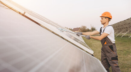 Engineer Cleaning Solar Panels in Outdoor Green Energy Facility