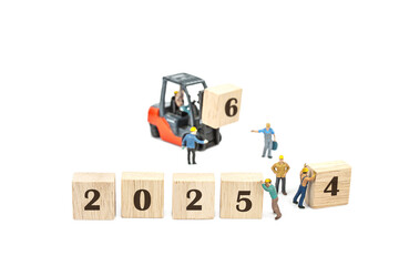 miniature worker team building standing front of forklift machine with 2025 number on wooden block...