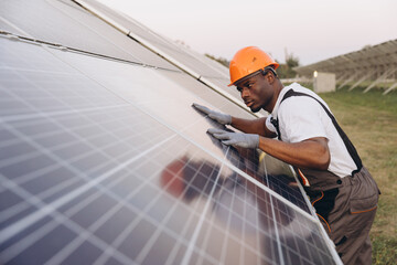 African American Male Engineer Inspecting Solar Panels at a Solar Farm