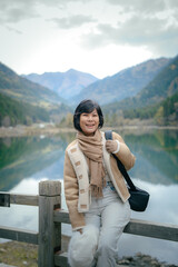 Happy travel girl standing by the mountain lake and looking at camera,  in lake at Dagu Glacier Park , China
