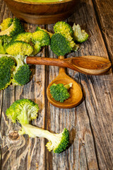 Fresh broccoli pieces with stalks and kitchen spoons on table