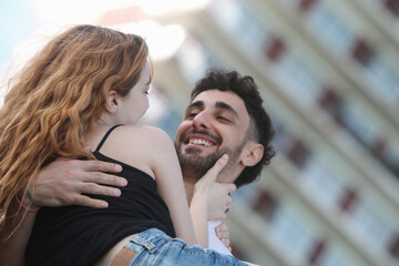 portrait of a young interracial loving couple having fun outdoors at the park. Young man carrying his girlfriend and smiling