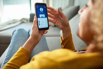 Woman checking mobile banking app on smartphone at home
