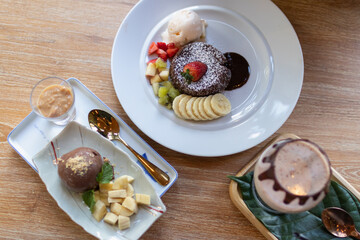 Delicious dessert arrangement featuring chocolate cake, fresh fruit, and ice cream served elegantly on a wooden table.