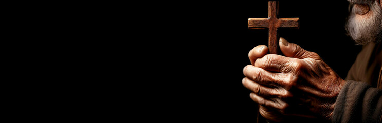 Extreme closeup of the wrinkled hands of old man holding a small wooden religious cross isolated on a black dark background with copy space, religious symbol of Christianity or prayer. Generative Ai.