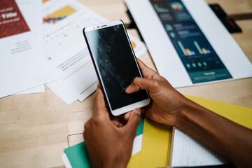 Faceless office worker browsing smartphone at workplace