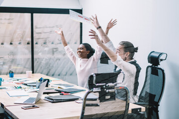 Diverse excited business people rejoicing in success during meeting in office