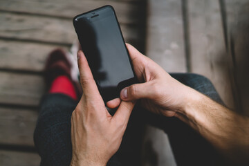Faceless person browsing smartphone on street