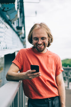 Laughing man in red t shirt surfing smartphone