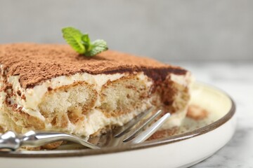 Piece of tasty tiramisu on white marble table, closeup