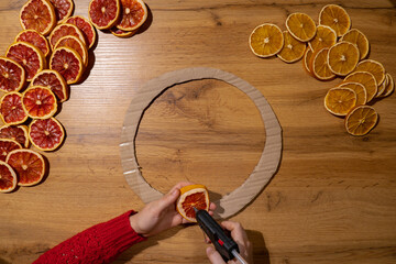 Step 1 Handmade Christmas wreath from dried orange grapefruit slices. Woman using hot glue Festive holiday preparation craft master class of creative making decor. Hands-on activities sustainable