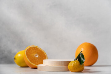 Wooden round podiums surrounded by citrus fruits on light background with copy space
