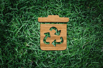 Eco-Friendly Waste Management: Wooden Trash Bin Icon with Recycling Symbol on Grass Background