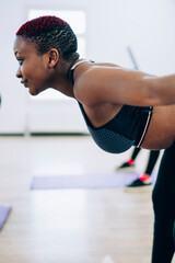 African American female looking at trainer and doing exercise