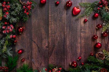 Stunning rustic Christmas background showcases a composition of bright red ornaments and lush pine branches against a textured dark wood background, ideal for holiday-themed decoration.