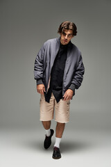 A young man confidently poses in a fashionable autumn outfit, highlighting his unique style and charm.