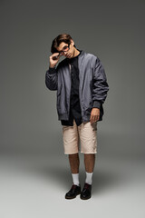 A young man stands confidently in an autumn outfit, highlighting his fashion sense and unique style.