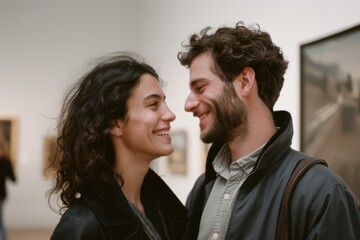 A joyful couple enjoys a tender moment in an art gallery, their eyes reflecting genuine affection and shared happiness within an artistic setting.