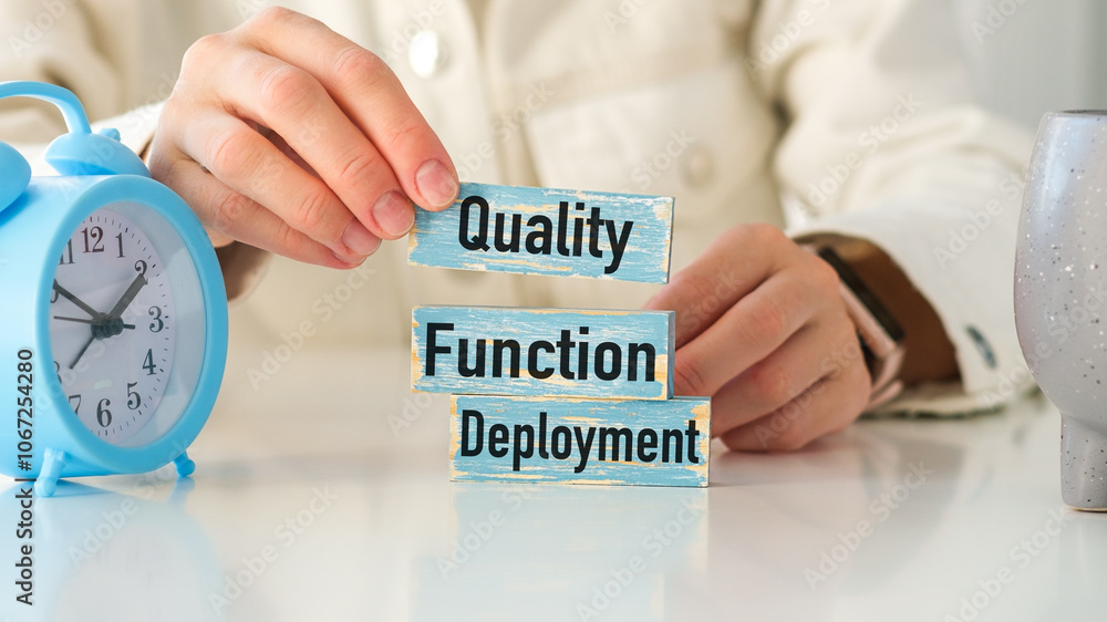 Poster a person holding up a blue clock and a stack of wooden blocks with the words quality function deploy