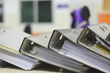 close-up view of several binders filled with documents and papers. The binders are stacked...