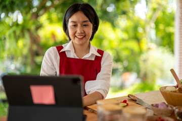 Asian chef using digital tablet while preparing ingredients for cooking