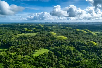 Obraz premium Lush Green Hills and Forested Landscape with a Blue Sky and White Clouds
