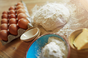 Above, eggs and flour with dough for ingredients, cooking or bread production in kitchen. Food, butter and nutrition with wood board and baking in home for dessert, culinary and pastry preparation