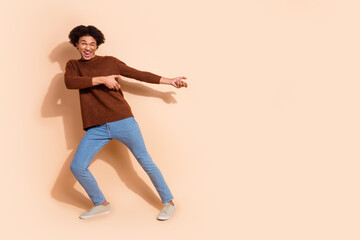 Young man pointing joyfully against beige background, expressing excitement and enthusiasm in casual outfit, perfect for promotional advertising and sales campaigns