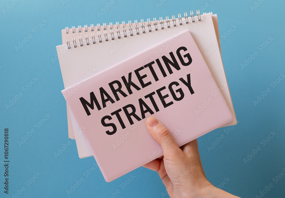 Poster marketing strategy text on a paper in hand with keyboard on blue background