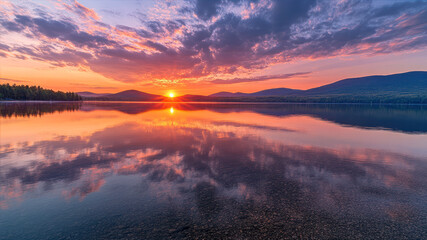 Obraz premium Breathtaking Sunrise Over Calm Mountains Reflecting in Serene Lake Water