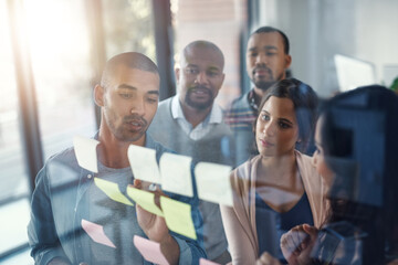 Obraz premium Discussion, glass and writing with business people in office for coaching, meeting or planning. Conversation, training or workshop with employee team at work with sticky notes on window for seminar