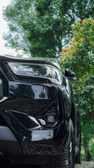 a black pickup truck's front end, showcasing the sleek headlight design and distinctive grille. The...
