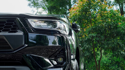 a black pickup truck's front end, showcasing the sleek headlight design and distinctive grille. The image highlights the vehicle's modern and aggressive styling. © AbiezaReswara