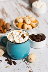 hot chocolate with marshmallows in a mug and cookies on a white table, closeup top view