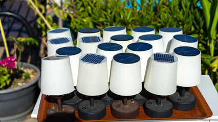 Table lamps with white shades on solar battery are charged from sun. Eco-friendly types of energy. Respect for environment