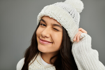 A young woman showcases her playful personality with a wink while dressed in warm winter clothing.