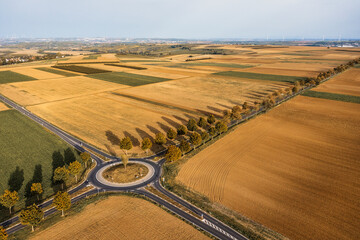 Bird's eye view of a roundabout in the middle of mown grain fields in autumn