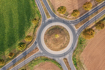 Bird's eye view of a roundabout in the middle of mown grain fields in autumn