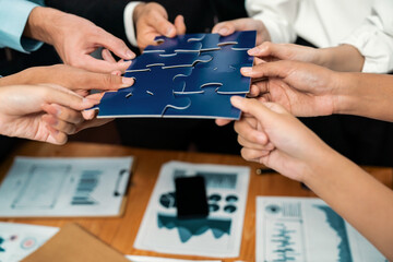 Multiethnic business people holding jigsaw pieces and merge them together as effective solution...