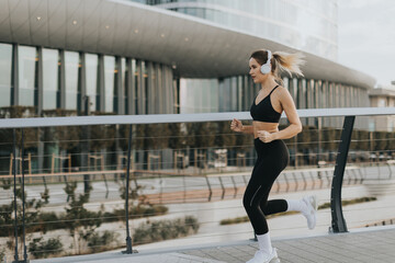 A woman jogging along a modern urban pathway in the early morning, embracing fitness and the vibrant city environment