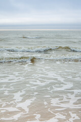 Wavy Baltic Sea with some foam, blue sky and green water, Ventspils, Latvia