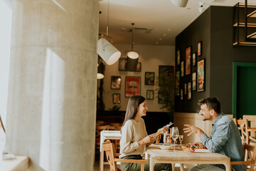 A joyful couple enjoying a delightful meal together at a cozy restaurant during a sunny afternoon