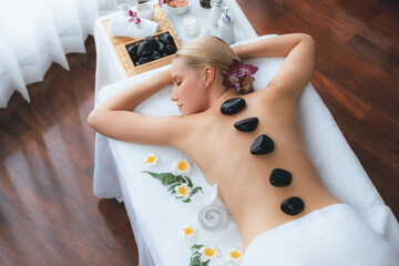 Hot stone massage at spa salon in luxury resort with day light serenity ambient, blissful woman...