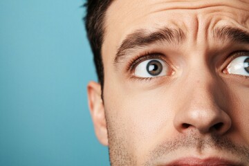 Fototapeta premium Close-up of a man's face showing surprise and concern against a blue background.