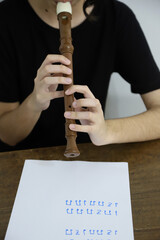 
Girl playing the flute following a sheet of music. Teenager learning music. Background with copy...